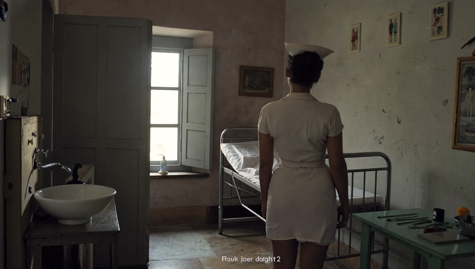 Interior of a small rural clinic in flat daylight with an empty metal examination bed and a nurse turned away from the camera
