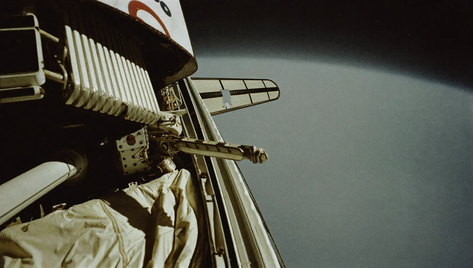 The open payload bay of a space shuttle orbiter in low Earth orbit with the curve of Earth's limb behind it