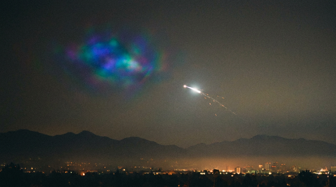 A brilliant glowing object in the night sky with a smaller bright object streaking away from it