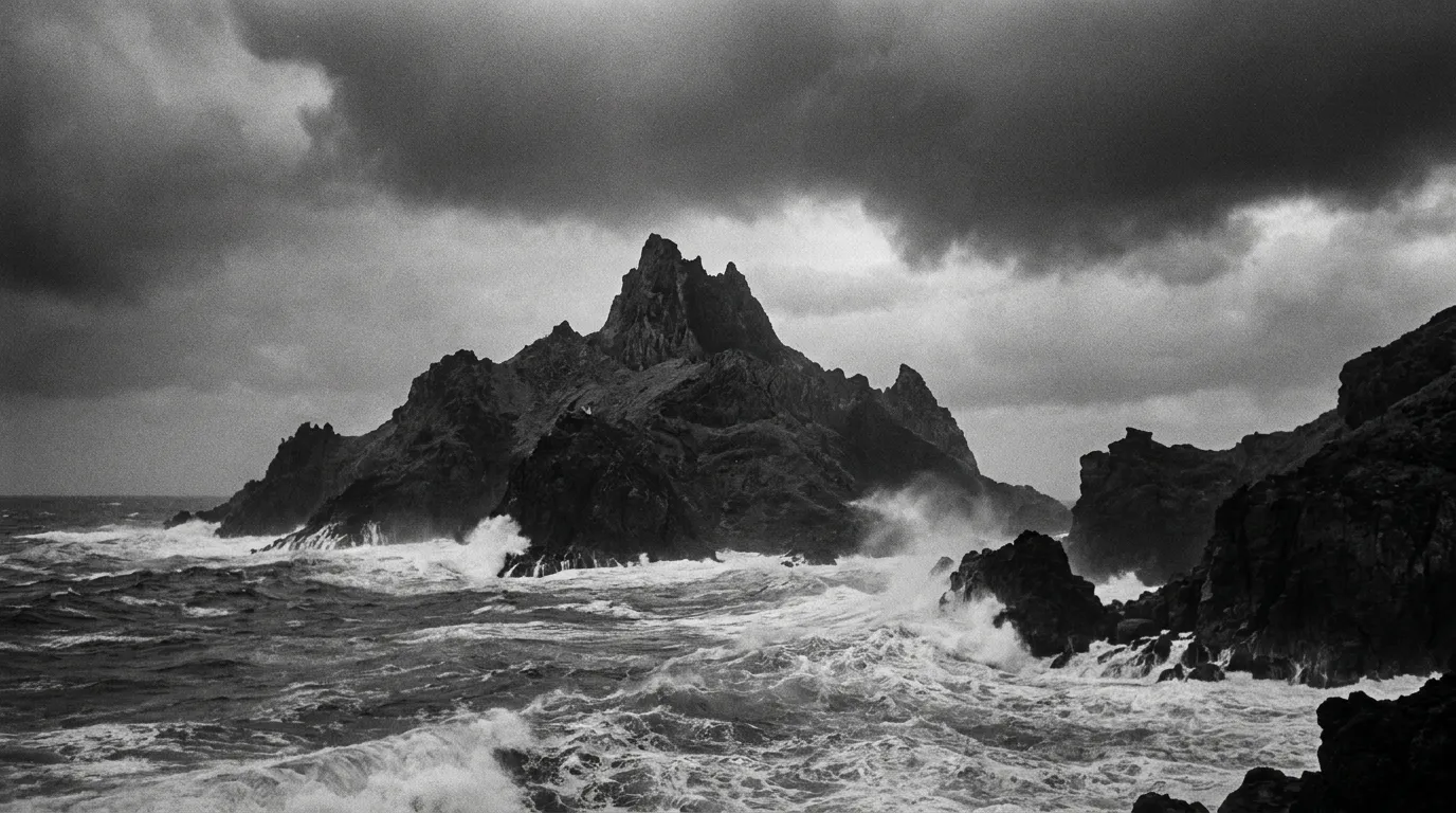 A rugged volcanic island with a jagged peak rising from a churning ocean